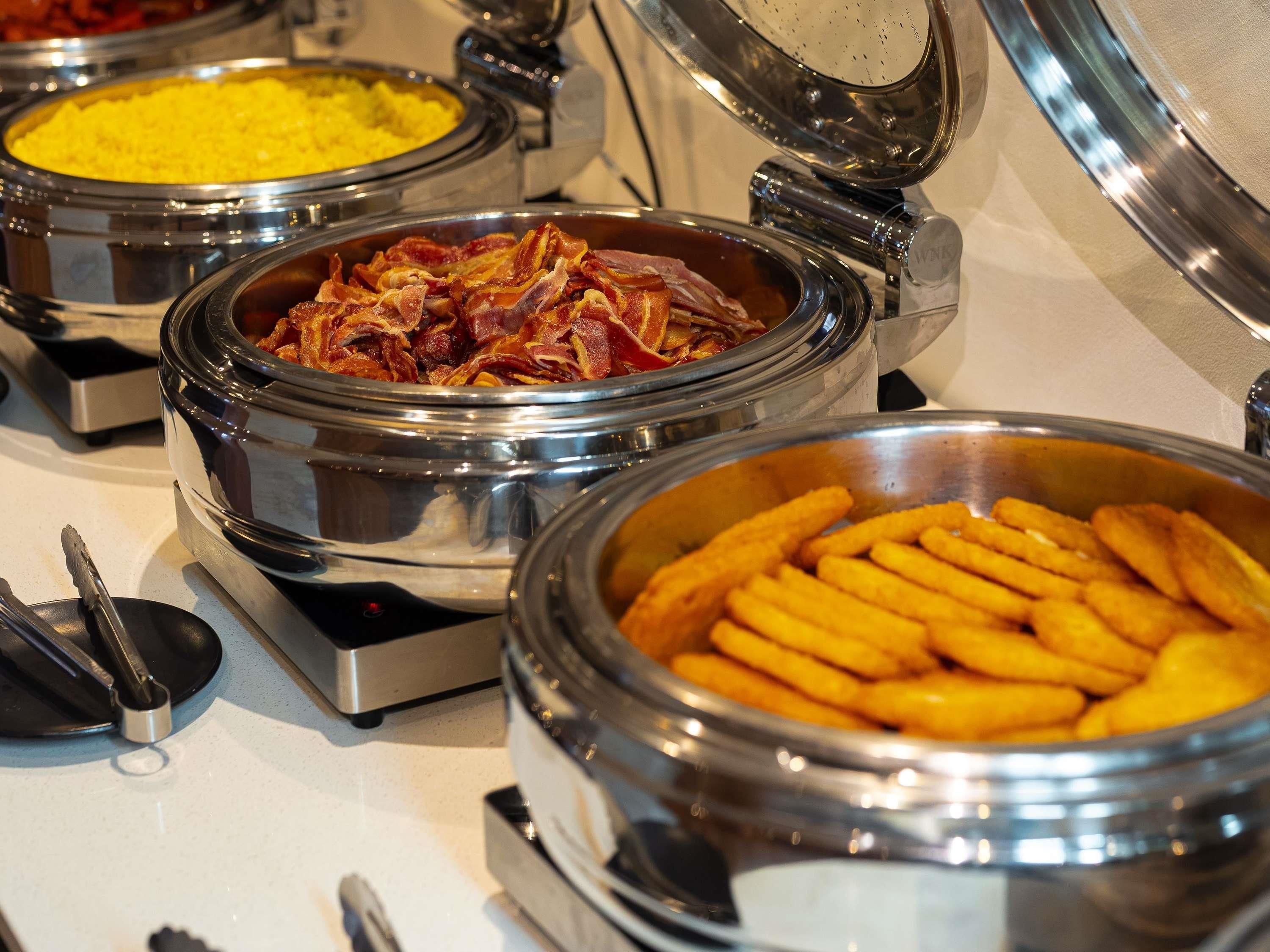 A buffet with various food items including fried potatoes and bacon.