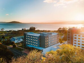 Un hotel moderno con varios pisos, techo plano y vista a un cuerpo de agua.