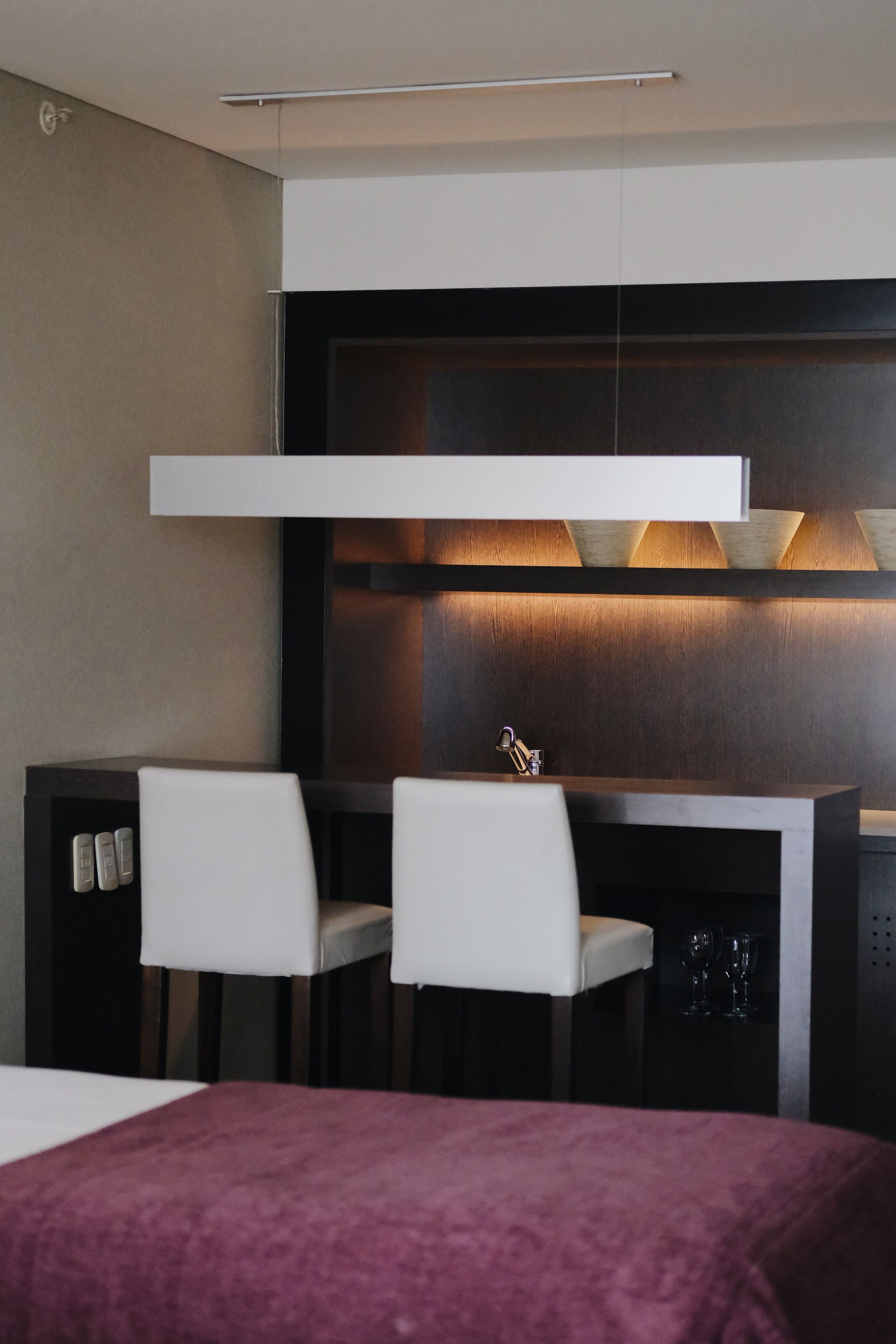 Ein modernes Hotelzimmer mit einem Bett, einem Schreibtisch mit zwei Stühlen und einer Minibar.