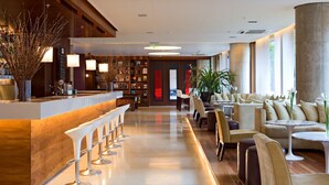 Een moderne hotellobby met een bar, zitplaatsen en een groot raam.