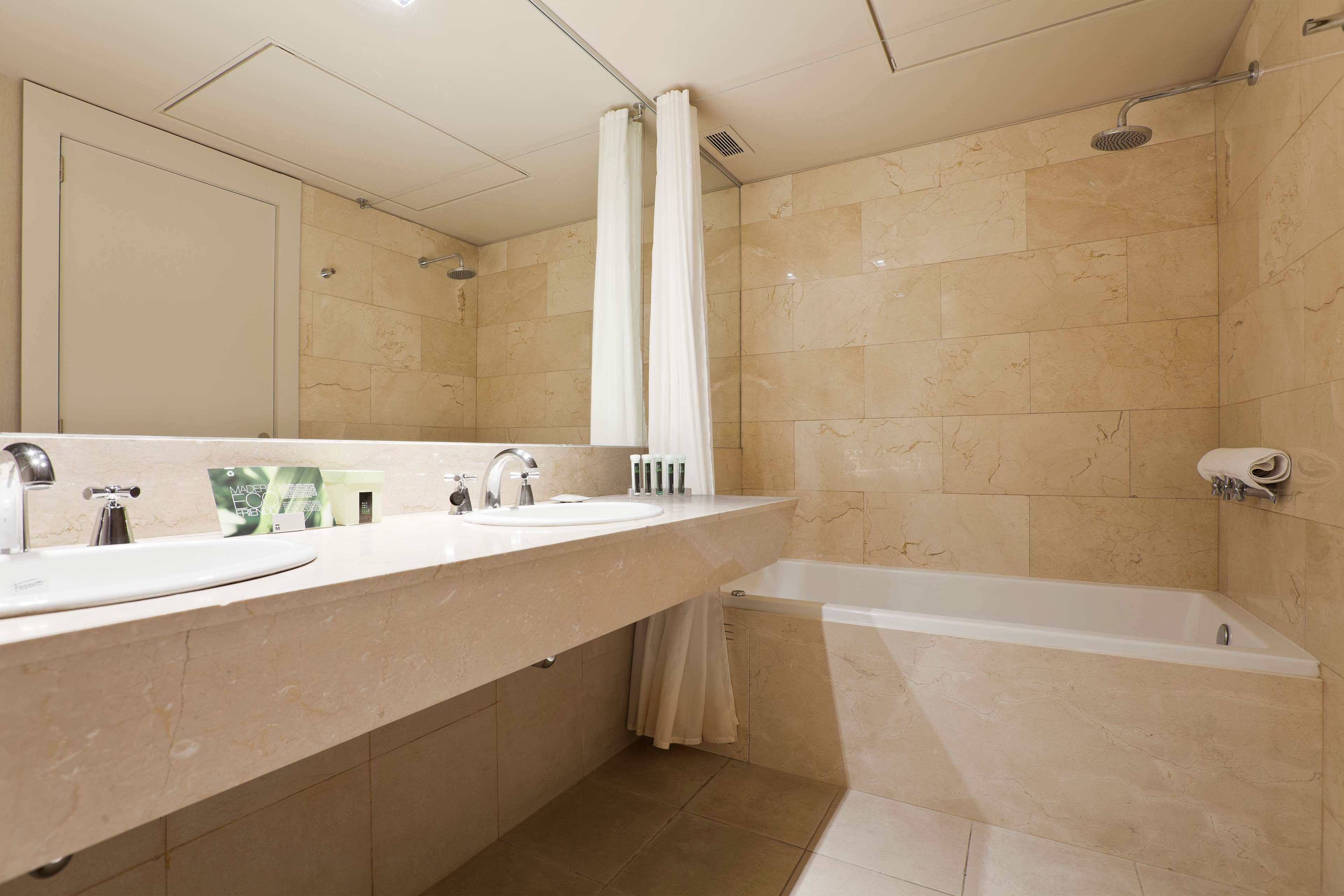 Un baño con dos lavamanos, una bañera y una ducha.