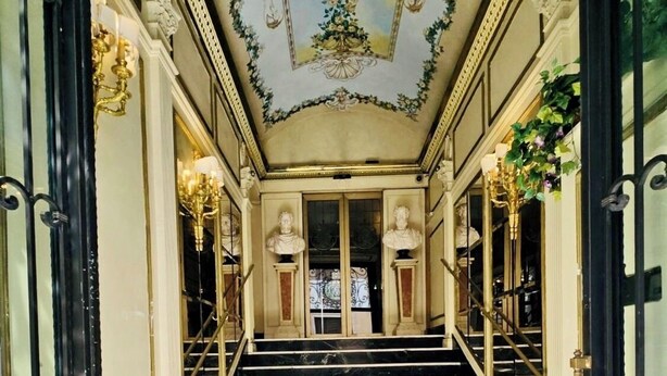 A grand hotel entrance with marble stairs, ornate ceiling decorations, and classical busts. - Champagne Palace Hotel (Rome)
