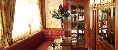 Ein luxuriöses Zimmer mit Holzbalkendecke, einem bequemen roten Sofa, einem Glastisch und einem roten Hocker.