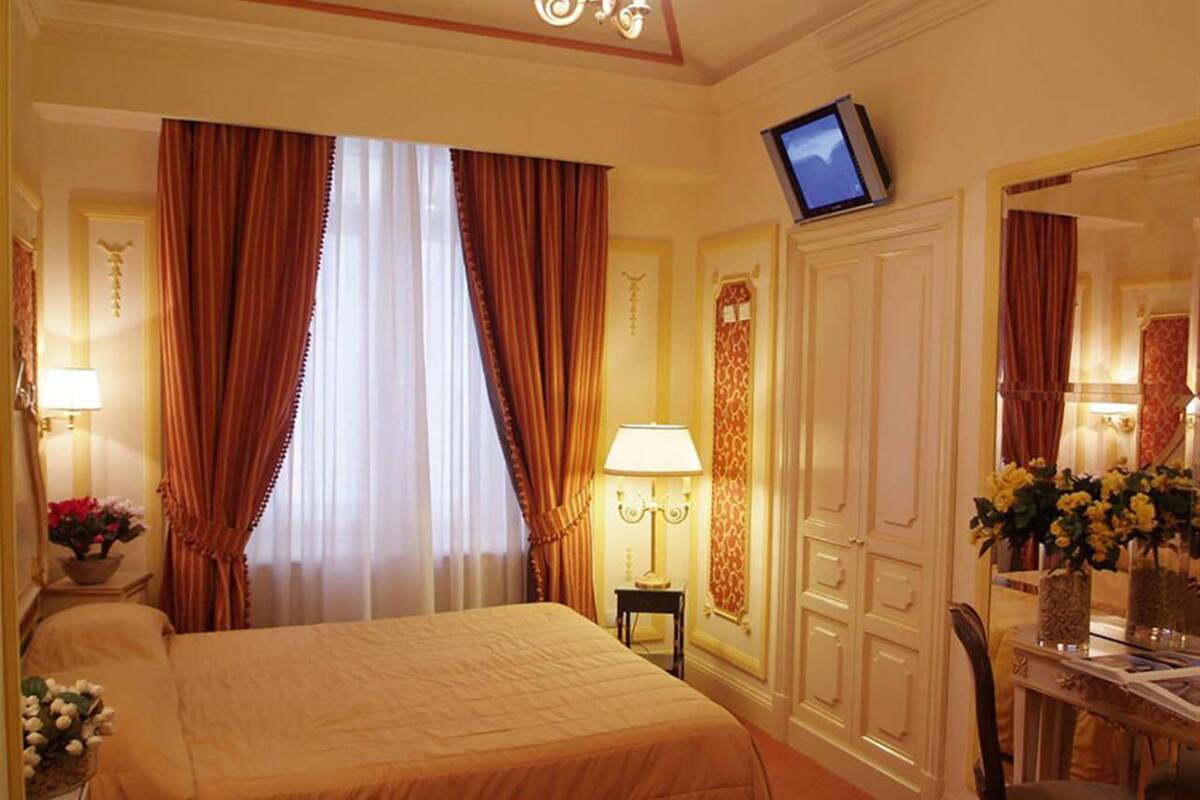 Une chambre d’hôtel avec un grand lit, un téléviseur fixé au mur, un bureau avec une chaise et un miroir.