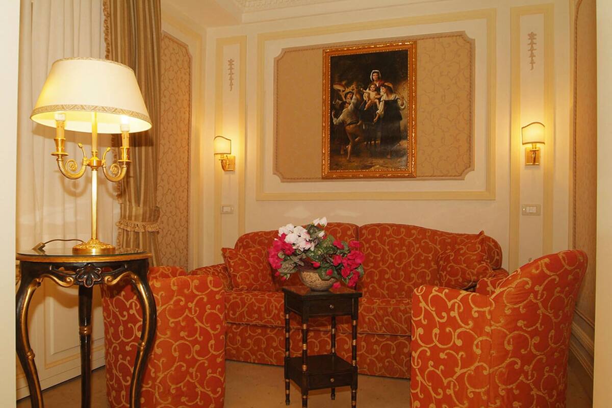 Une pièce comprenant un canapé, une petite table avec une lampe et un tableau accroché au mur.