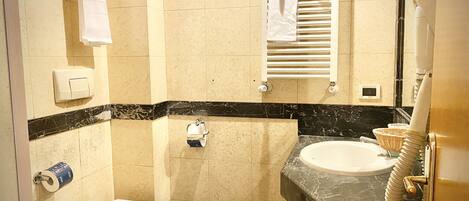 A bathroom with a toilet, sink, towel rack, and a shower area.