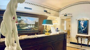 A marble reception desk with a statue, a painting, and a lamp. - Champagne Palace Hotel (Rome)