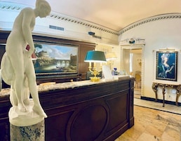 A marble reception desk with a statue, a painting, and a lamp.