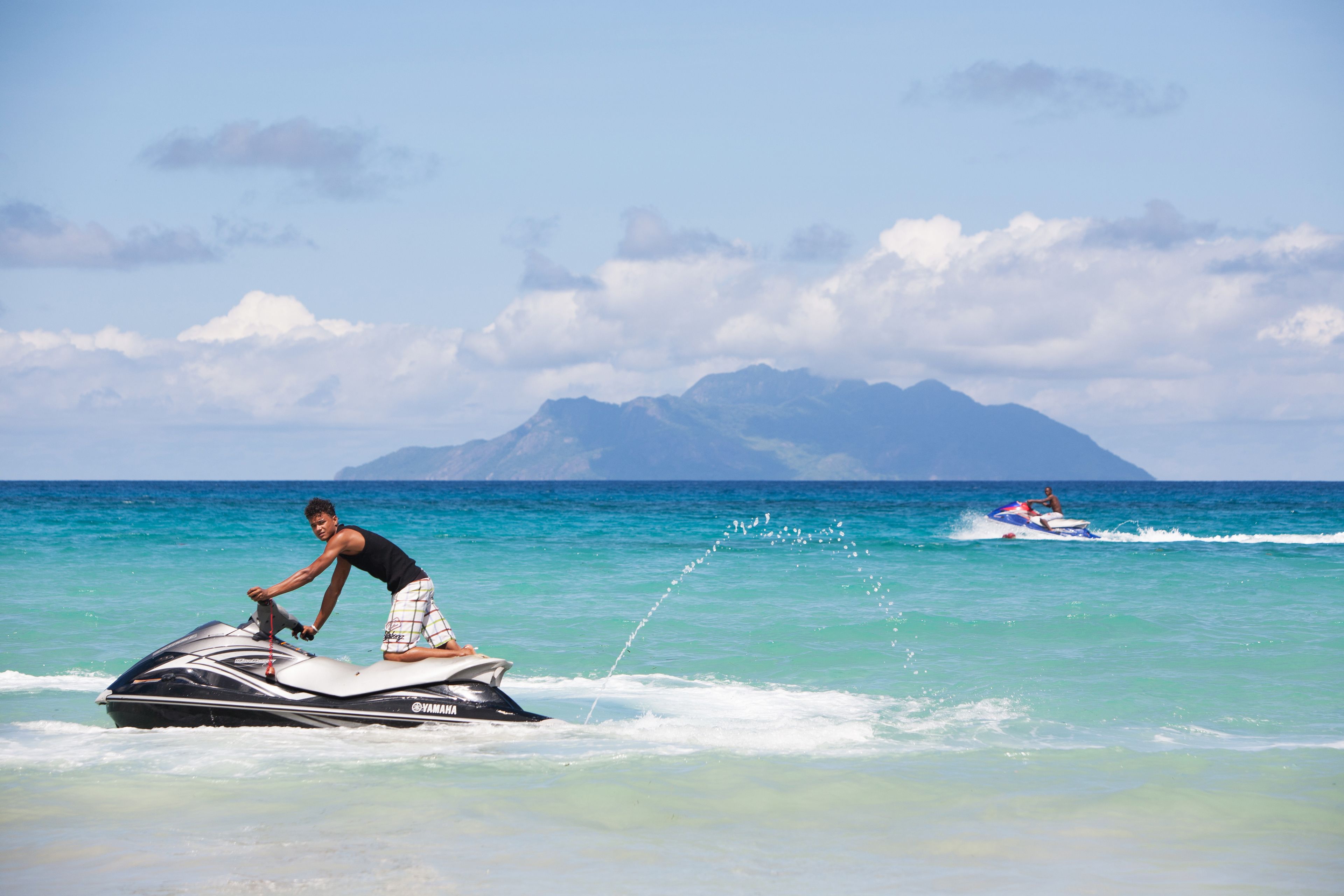 A jet ski on a clear blue sea with a mountainous island in the background.