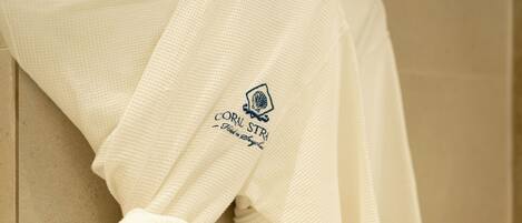 A white towel with a logo and text, hanging on a beige wall.