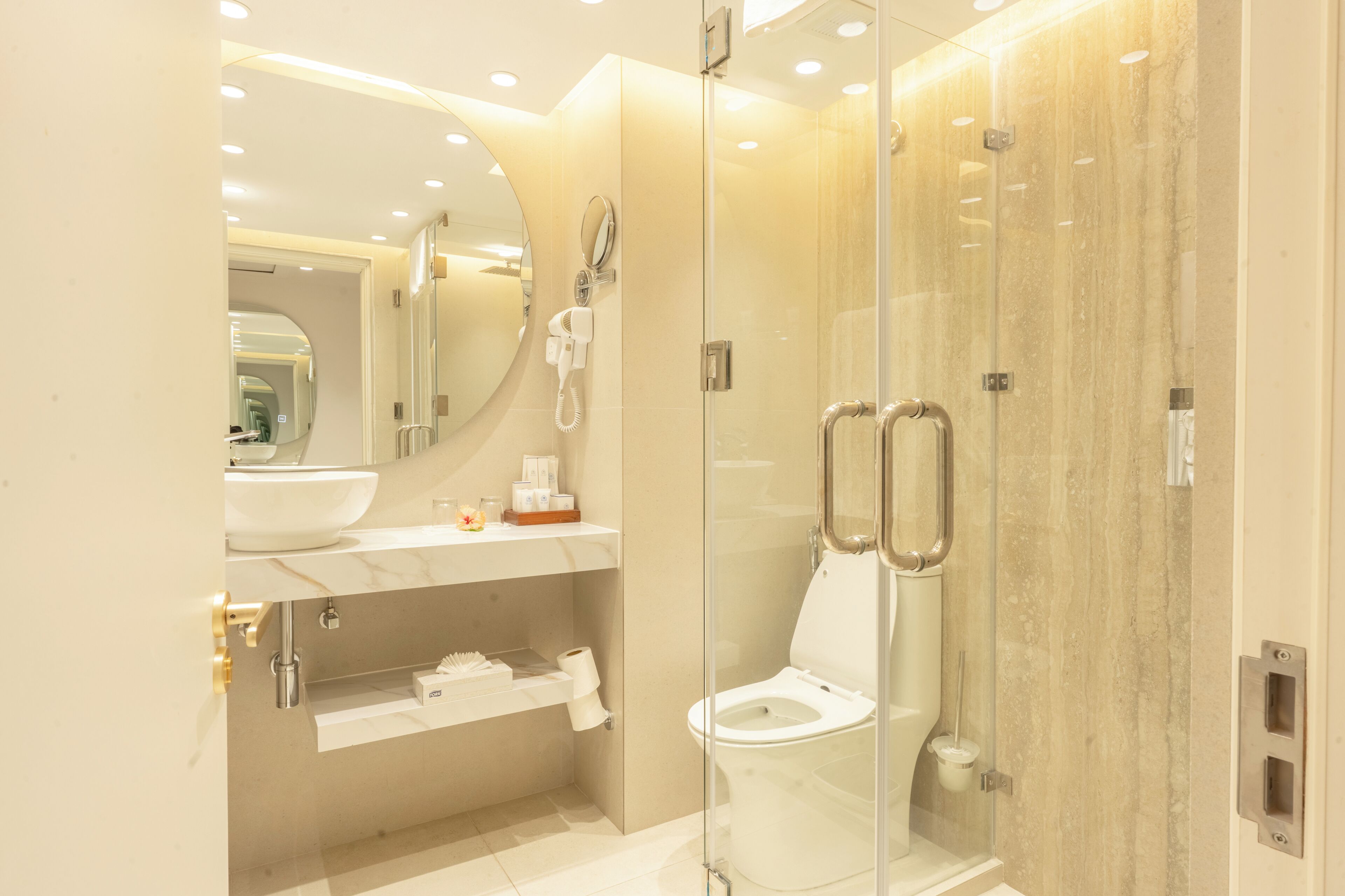 A modern bathroom with a glass-enclosed shower, a white sink, and a toilet.