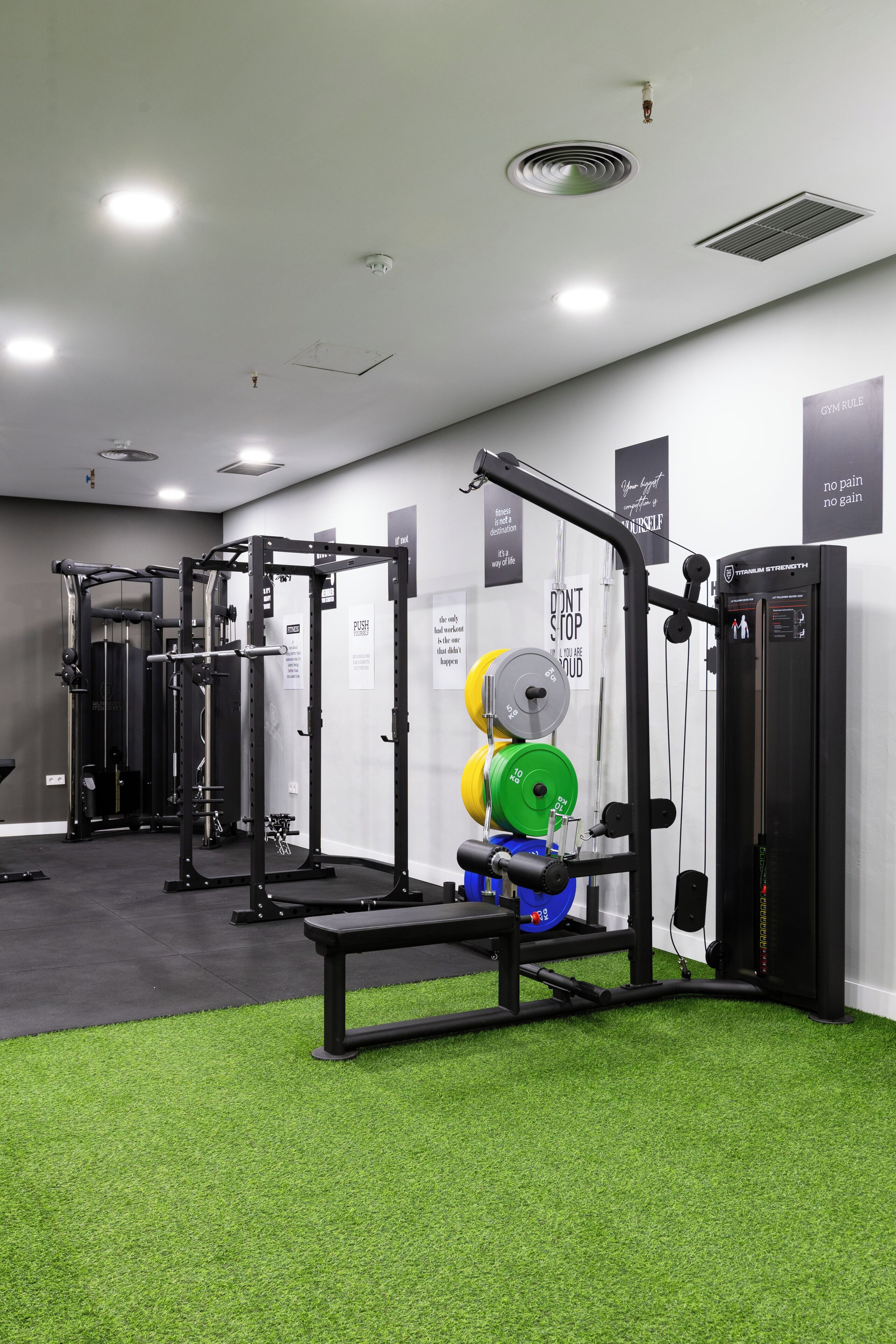 Un gimnasio con equipo de levantamiento de pesas, una banca y una pared con carteles motivacionales.
