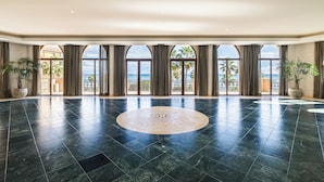 Un lobby amplio con un gran piso de diseño circular, ventanas arqueadas y plantas en macetas.