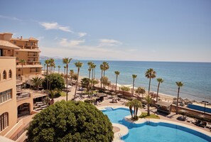 Un resort con piscina, palmeras y vista al mar.