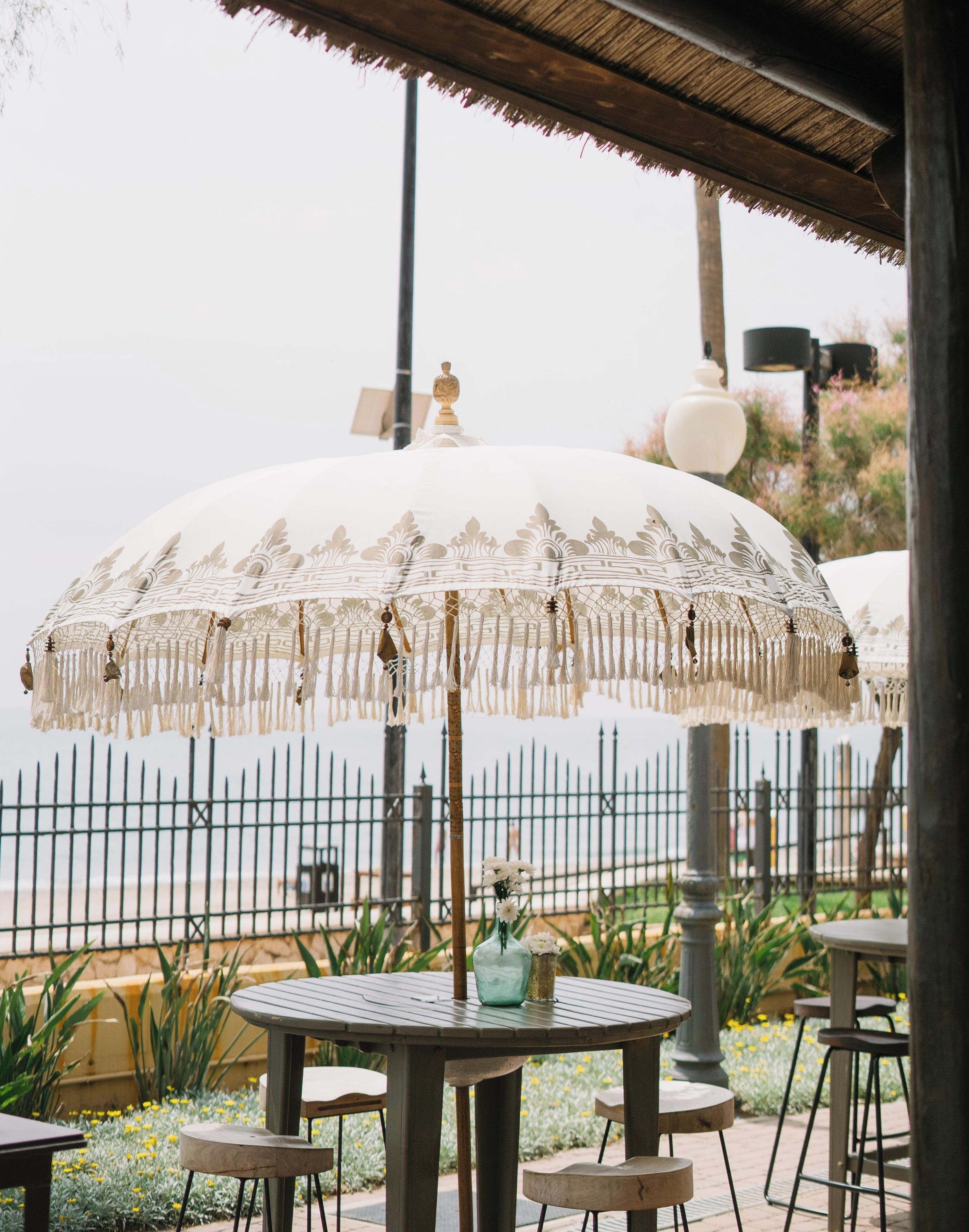 An outdoor seating area with round tables and a large decorative umbrella.