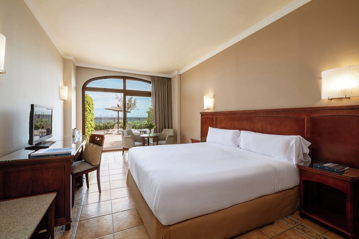 Een hotelkamer met een groot bed, een bureau met een computer, een stoel en uitzicht op de omgeving.