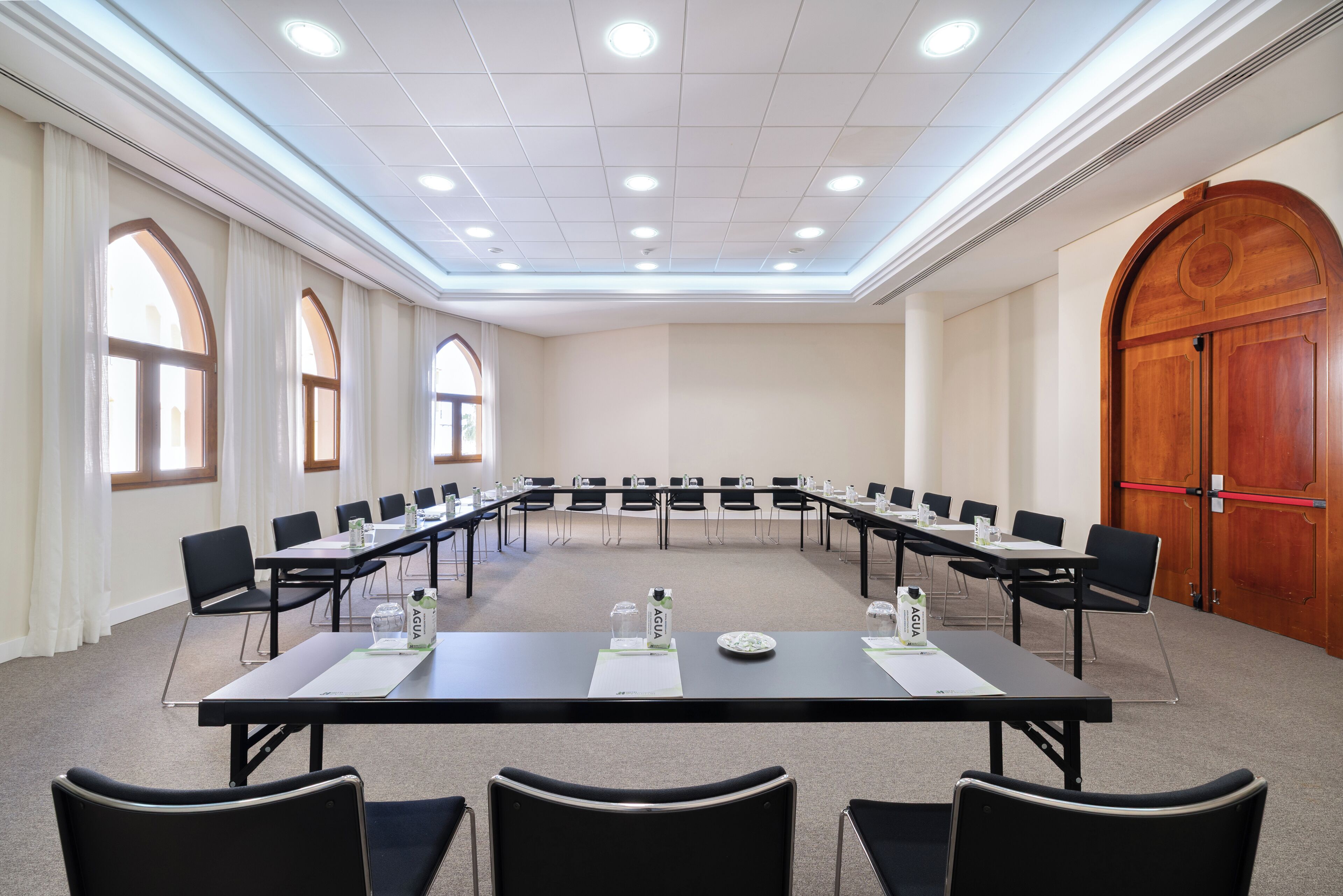 Un salón de conferencias con una larga mesa, sillas y placas de identificación.