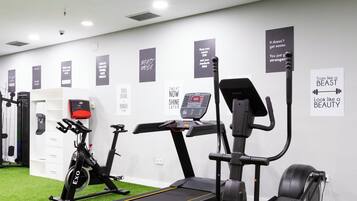 Et fitnessrum med løbebånd, crosstrainere og en motionscykel.