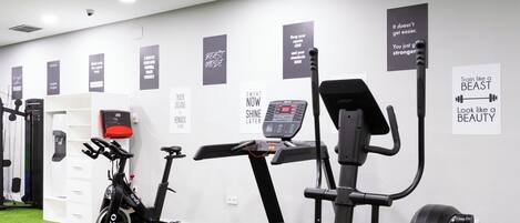 Un gimnasio con cintas de correr, elípticas y una bicicleta estática.