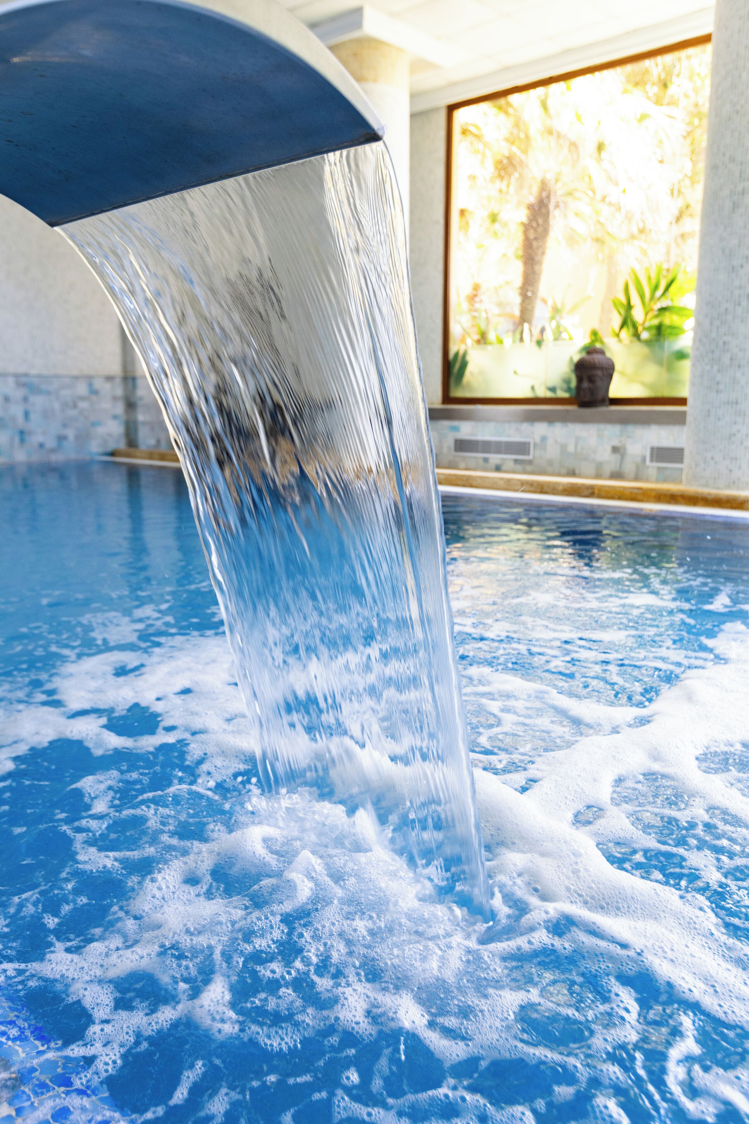 Ein Pool mit glatter Wasseroberfläche und einer sichtbaren Springbrunnenanlage.