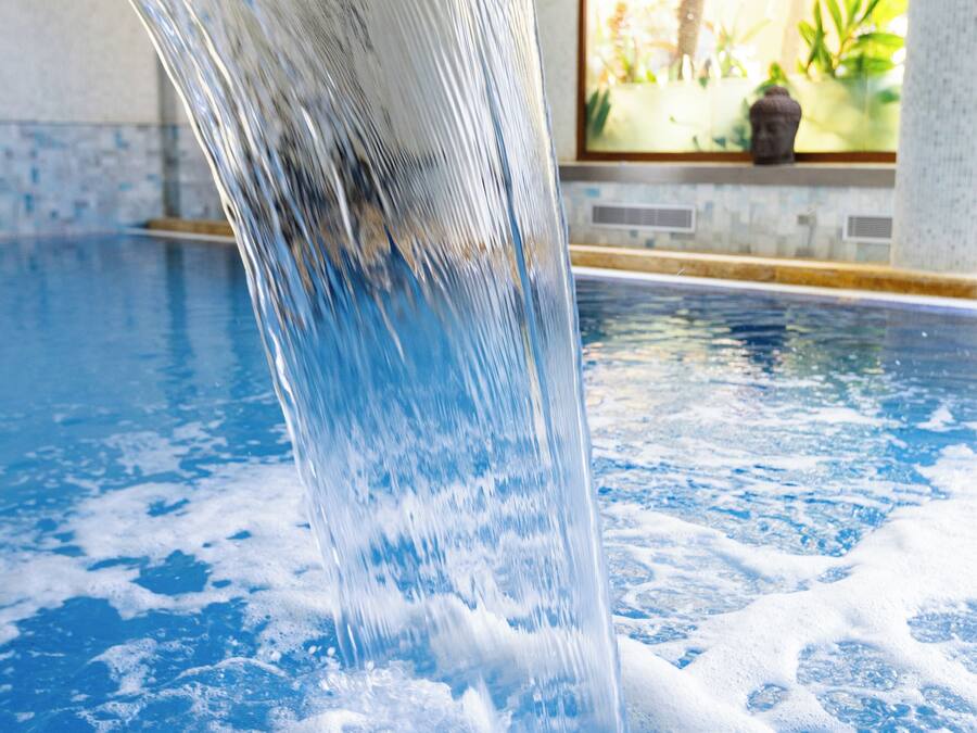 Una piscina con superficie de agua cristalina y una fuente visible.