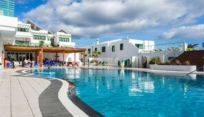 A pool area with a covered seating area, lounge chairs, and a building with a white facade and green accents. - BLUESEA Los Fiscos (Tías)