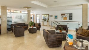 A spacious lobby with wicker furniture, a glass coffee table, and a staircase leading to an upper level. - BLUESEA Los Fiscos (Tías)