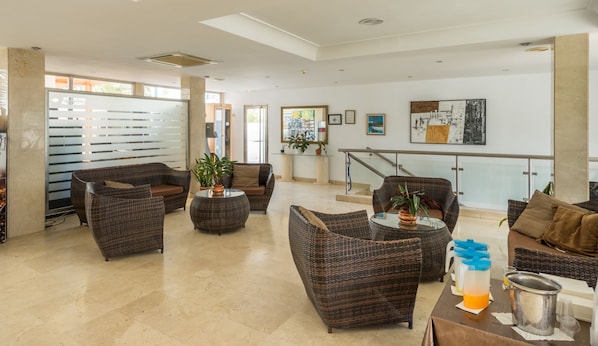 A spacious lobby with wicker furniture, a glass coffee table, and a staircase leading to an upper level. - BLUESEA Los Fiscos (Tías)