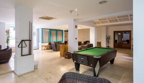 A pool table in a well-lit room with a billiards table, seating area, and a door leading to another room. - BLUESEA Los Fiscos (Tías)
