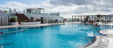 Una piscina al aire libre, sillones reclinables de piscina