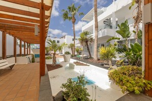 A modern outdoor area with a wooden pergola, a water feature, and various plants. - BLUESEA Los Fiscos (Tías)