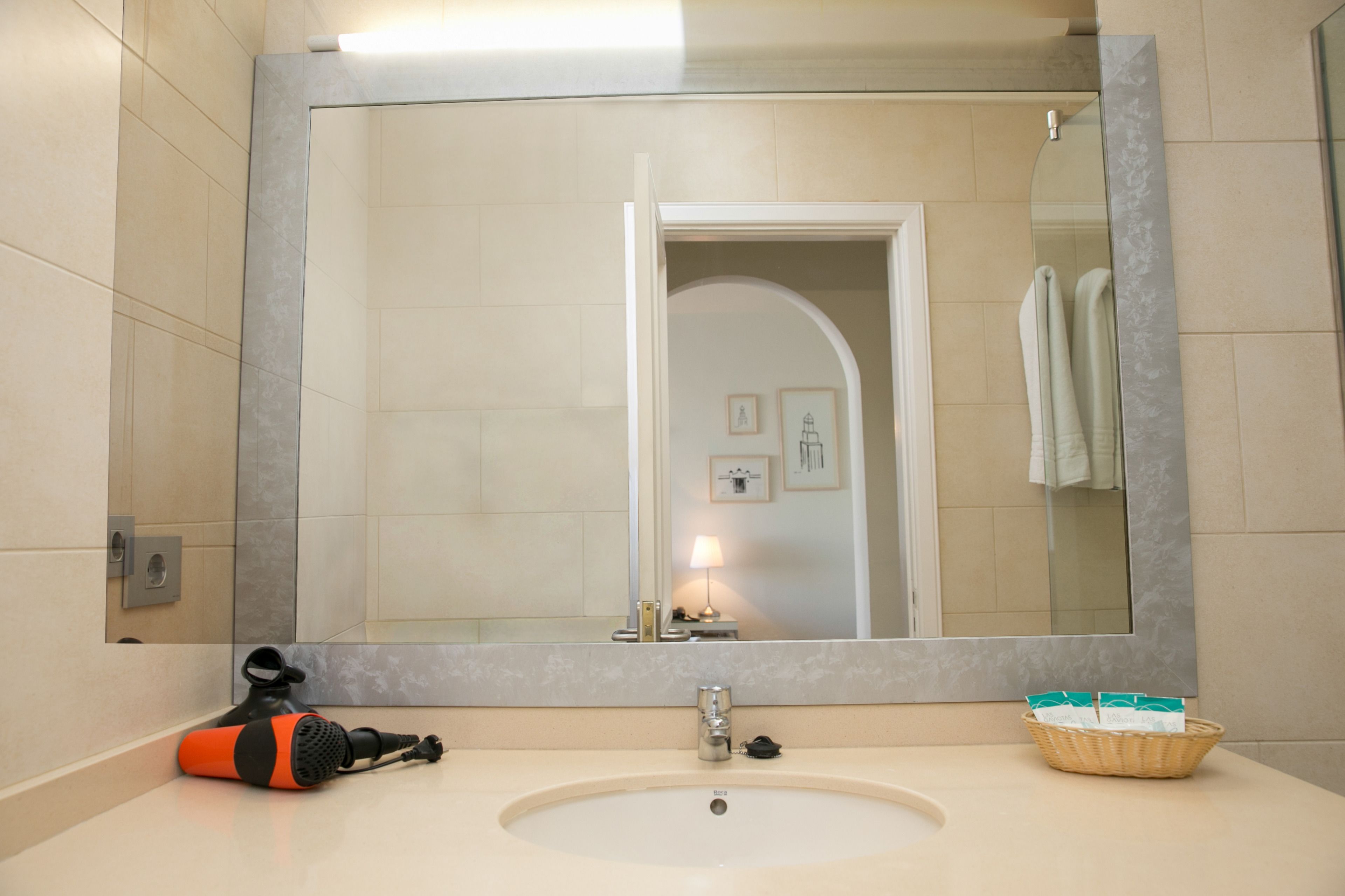 A bathroom with a large mirror, a sink, and a towel rack.
