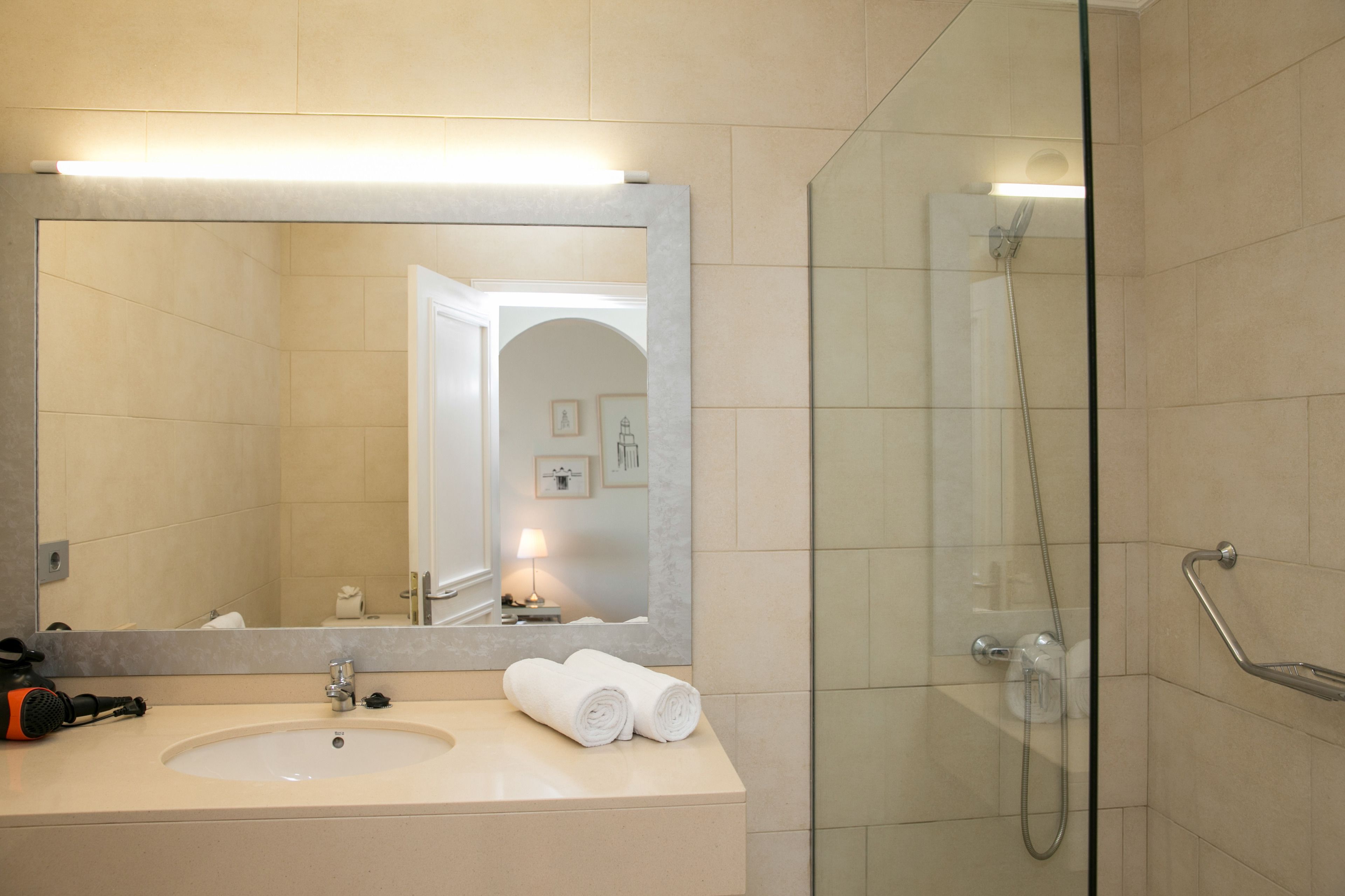 A bathroom with a sink, mirror, and shower.