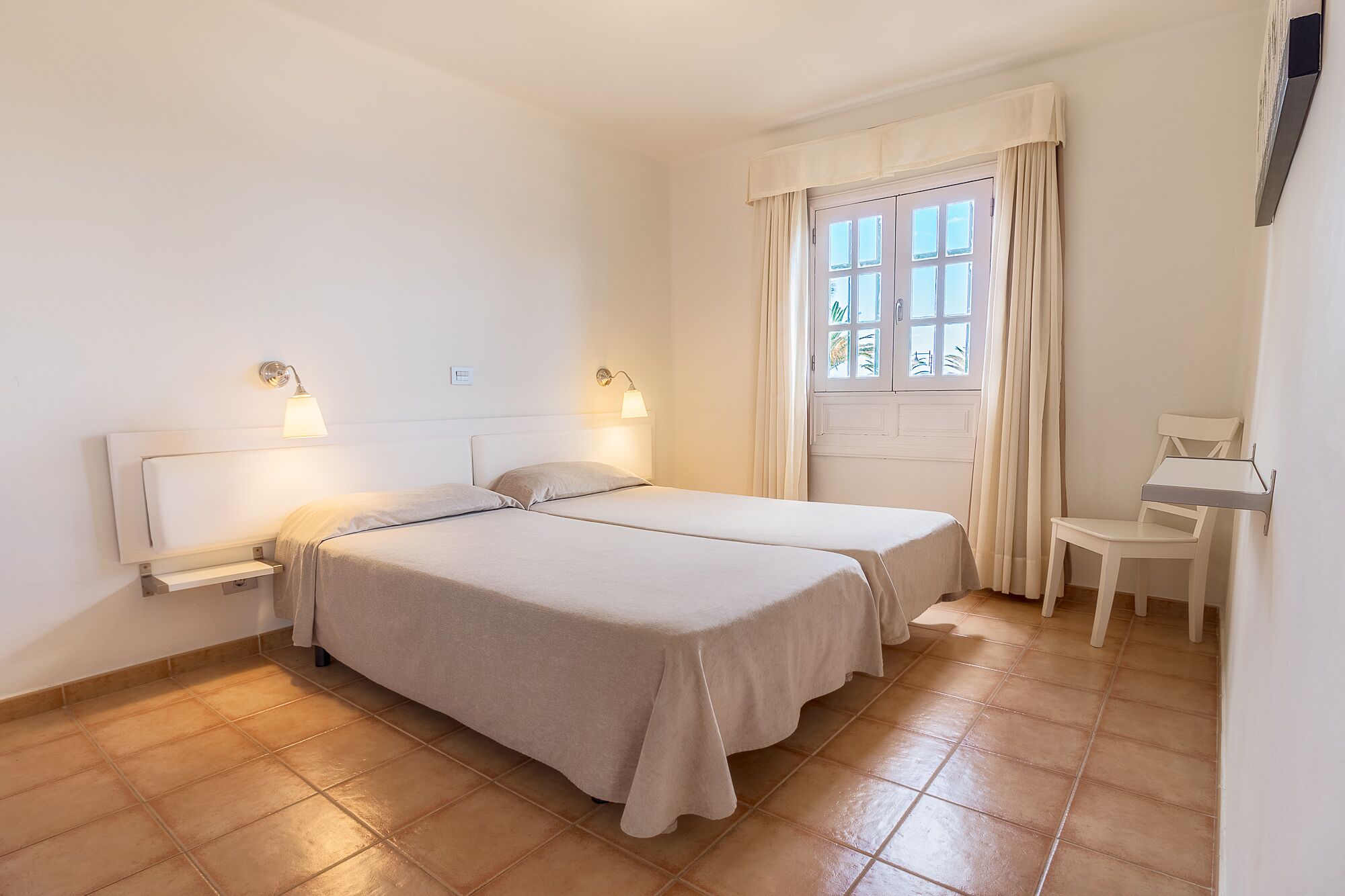 A room with two beds, a desk, and a chair.
