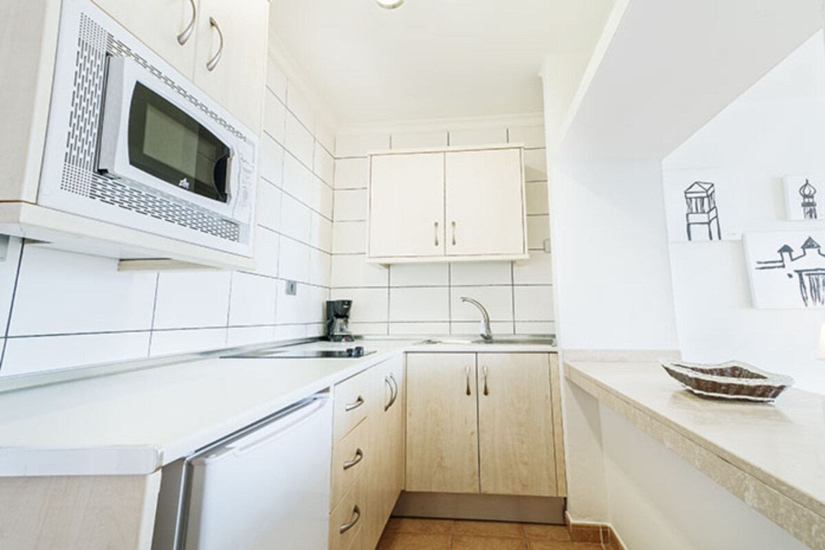 A modern kitchen with white cabinets, a microwave, and a sink.
