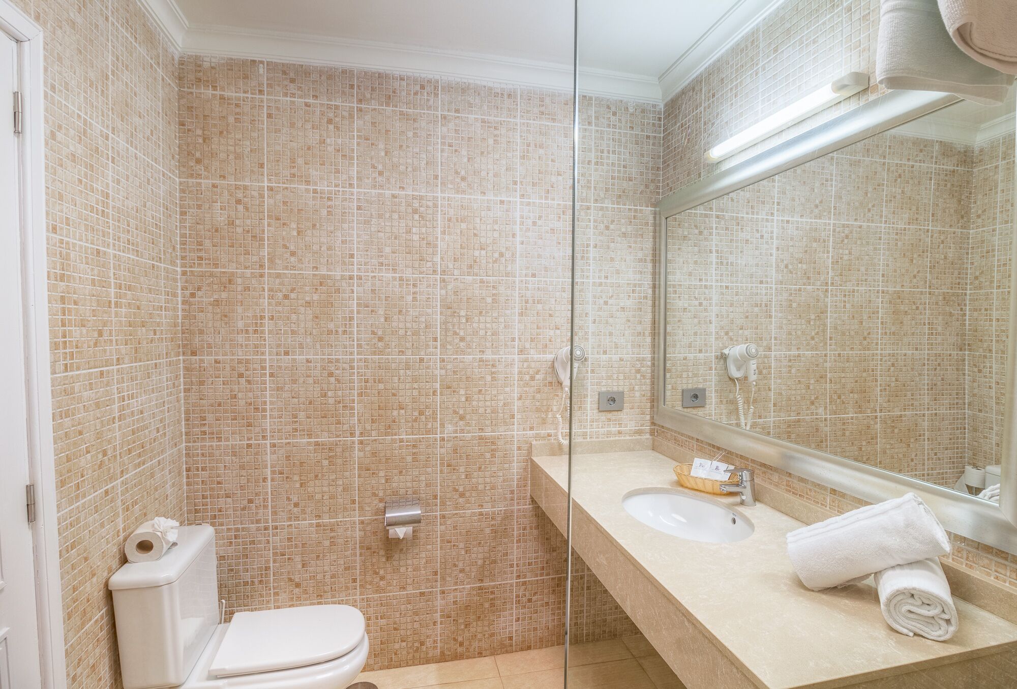 A bathroom with a toilet, sink, and mirror.