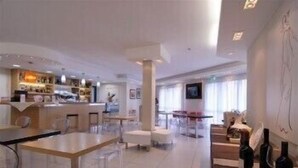 A modern hotel lobby with a bar area, seating arrangements, and wine bottles.