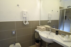 A modern bathroom with a white sink, a mirror, and a towel dispenser.