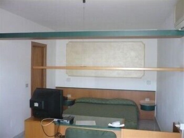 Habitación pequeña con literas, un escritorio junto a una silla, una maleta y una ventana con vista al mar.