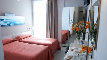 Habitación de hotel con dos camas, un espejo grande, un cuadro en la pared y una mesa con un jarrón de flores.