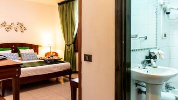 Ein Hotelzimmer mit Bett, Nachttisch, Lampe und Vorhängen.