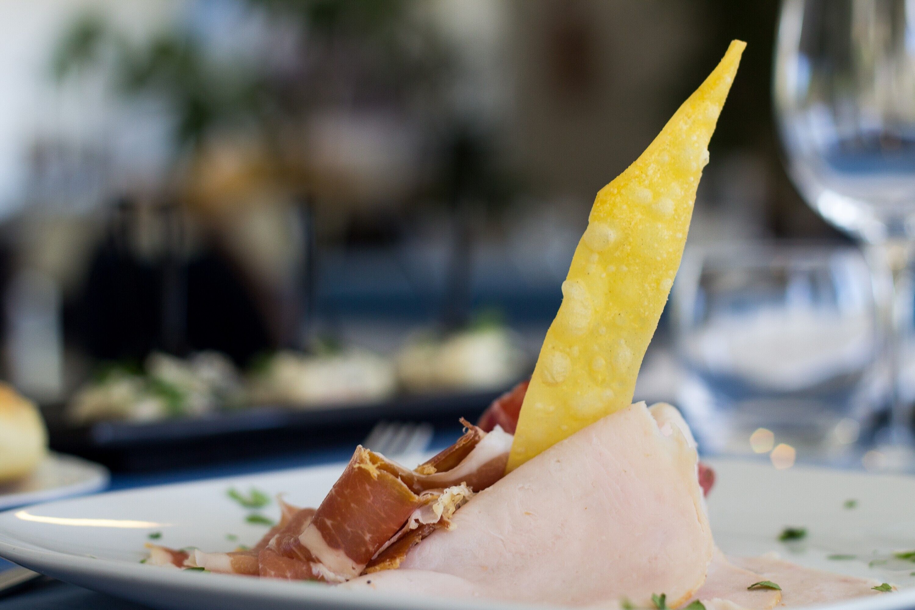 A plate with sliced meat and a yellow garnish.