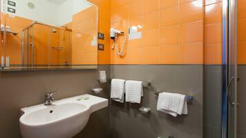 Un baño con lavamanos blanco, espejo y paredes con azulejos naranjas.