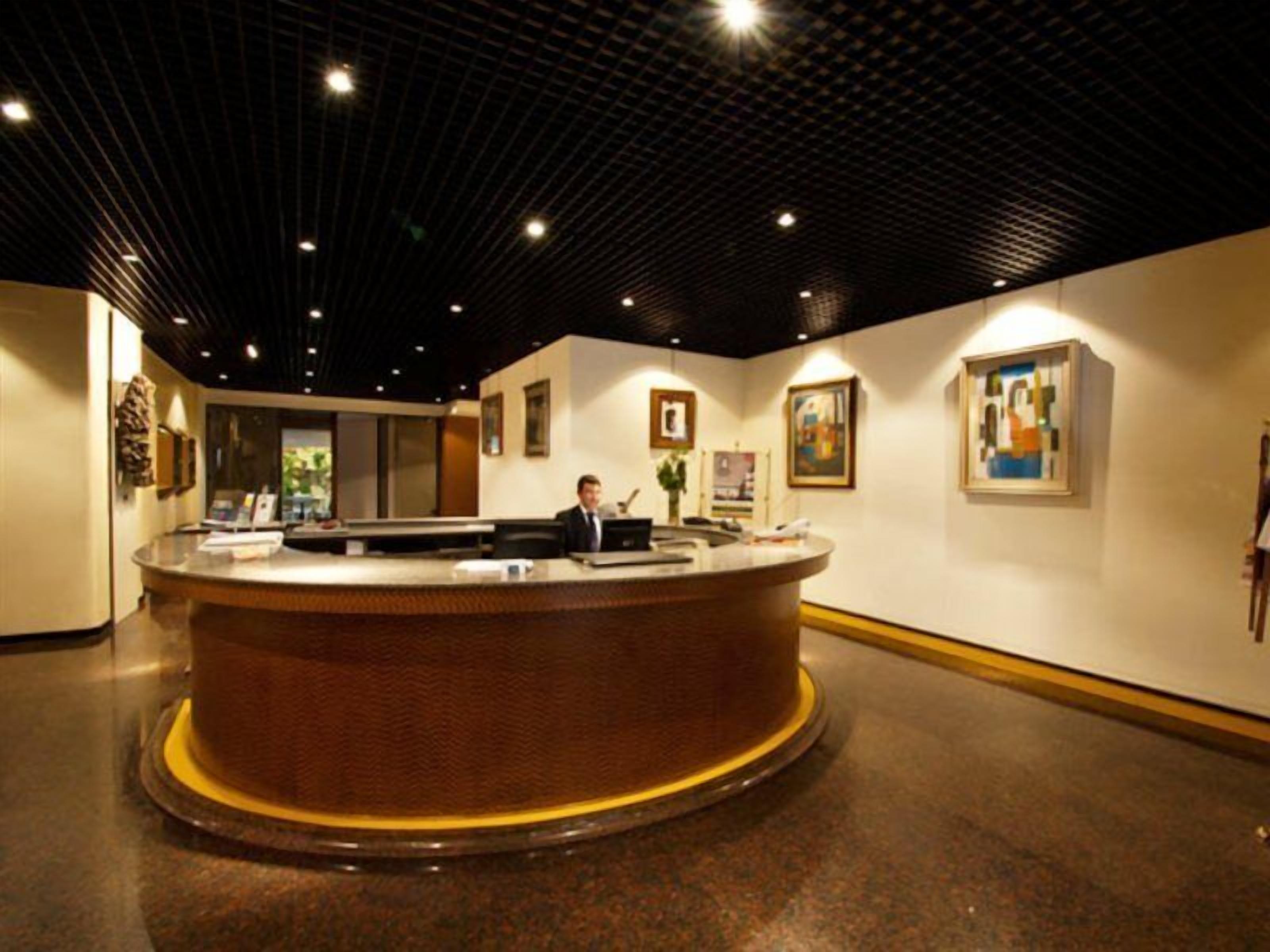 A reception area with a round counter, a receptionist, and framed artwork on the walls.