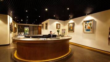 A reception area with a round counter, a receptionist, and framed artwork on the walls.