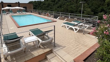 A rooftop pool area with lounge chairs and a swimming pool.