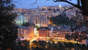 Paisagem urbana ao entardecer, com edifícios, ruas e árvores.