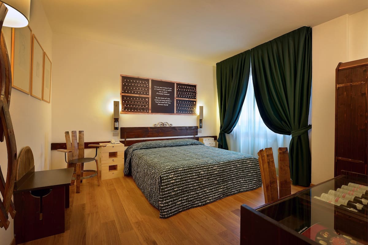 A bedroom with a wooden bed, a desk, a chair, and a large wall-mounted bulletin board.
