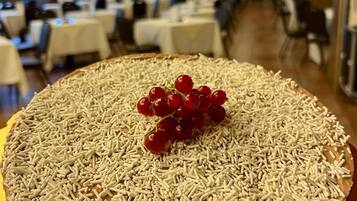 Un postre grande y redondo con chispas y uvas rojas sobre una mesa en un restaurante.