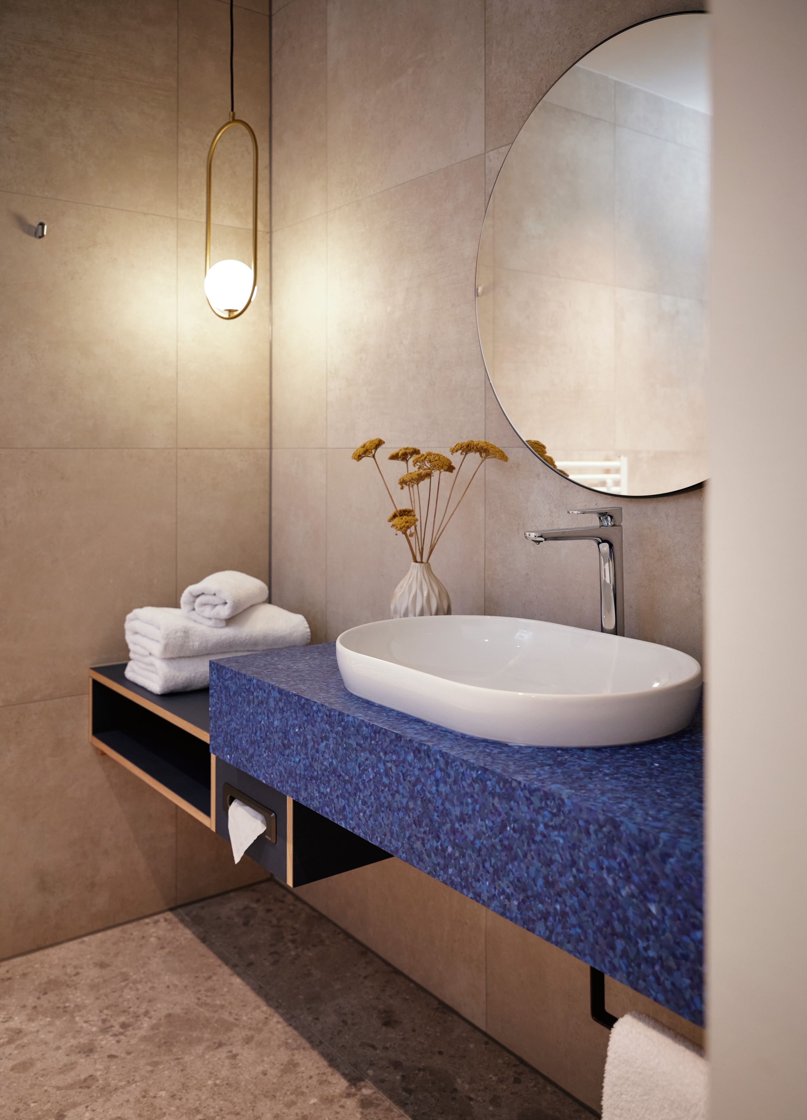 Un baño moderno con una encimera azul, lavamanos blanco y un espejo grande.